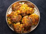 Golden brown crispy smashed potatoes on an oval white plate on a dark textured background.