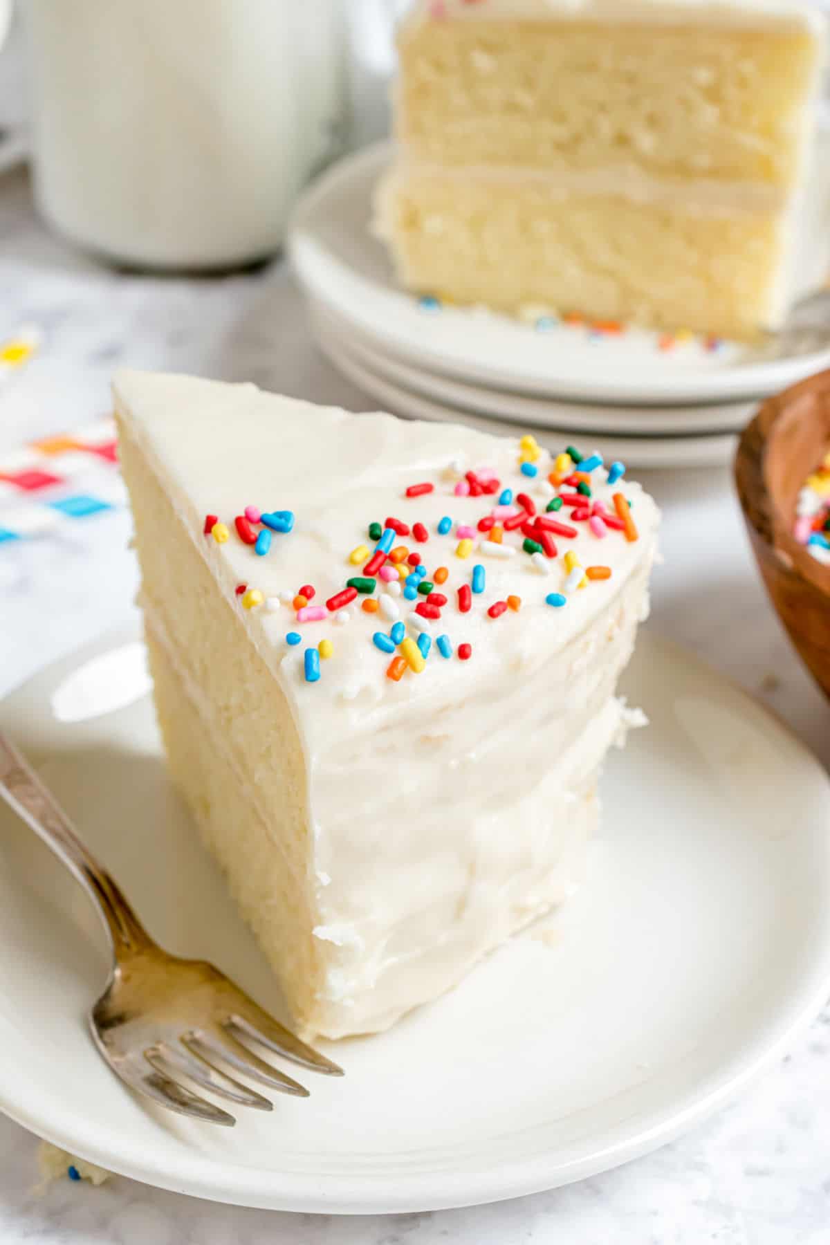 Vanilla sour cream frosting on a slice of cake with sprinkles.