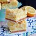 Stack of two lemon cheesecake bars on a flower linen napkin.