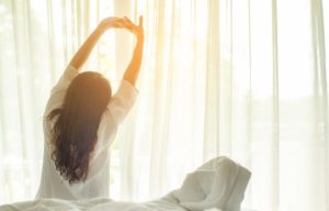 A woman waking up to the sunrise.