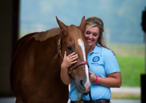 Equine student standing with horse in the stable