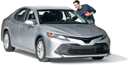 A young man reaches into his driver’s side window.