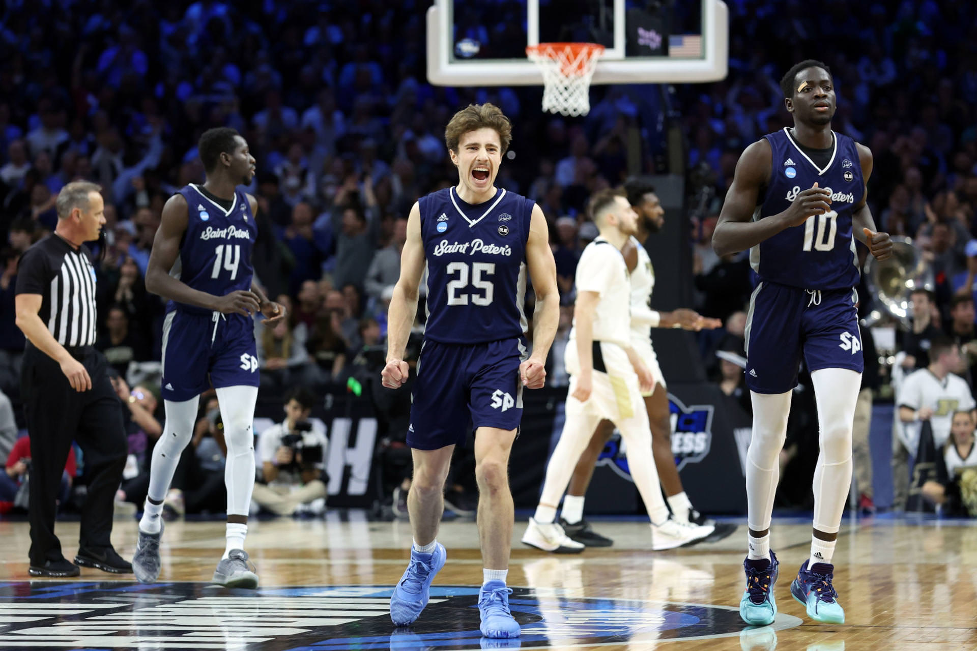 St. Peter's Peacocks guard Doug Edert (25) and forward Fousseyni Drame (10) and forward Hassan Drame (14) celebrate after a play