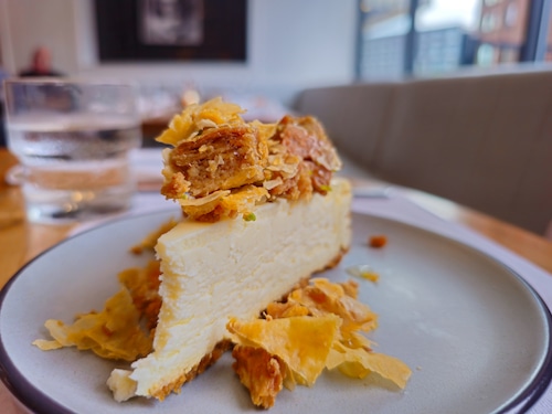 A slice of cheesecake topped with crumbled baklava.