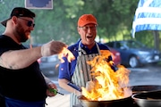 Chefs at the St. Sophia's Greek Cultural Festival in Syracuse react to the flames of pan-seared Saganaki (fried Greek cheese) in Syracuse on Thursday, June 6, 2024. (Katrina Tulloch | ktulloch@syracuse.com)