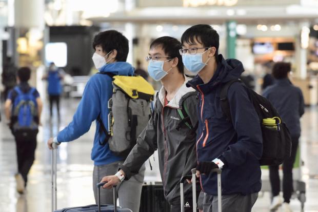 Inbound passengers wearing masks walk through the arrivals hall at Hong Kong International Airport