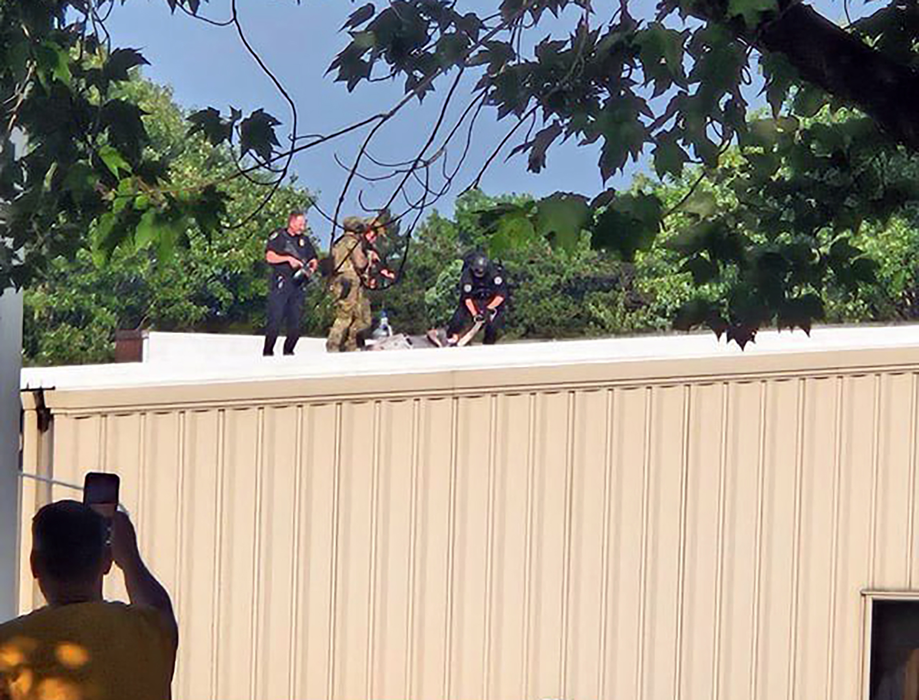 Police surround the body of the shooter on a roof nearby to where Donald Trump was addressing supporters