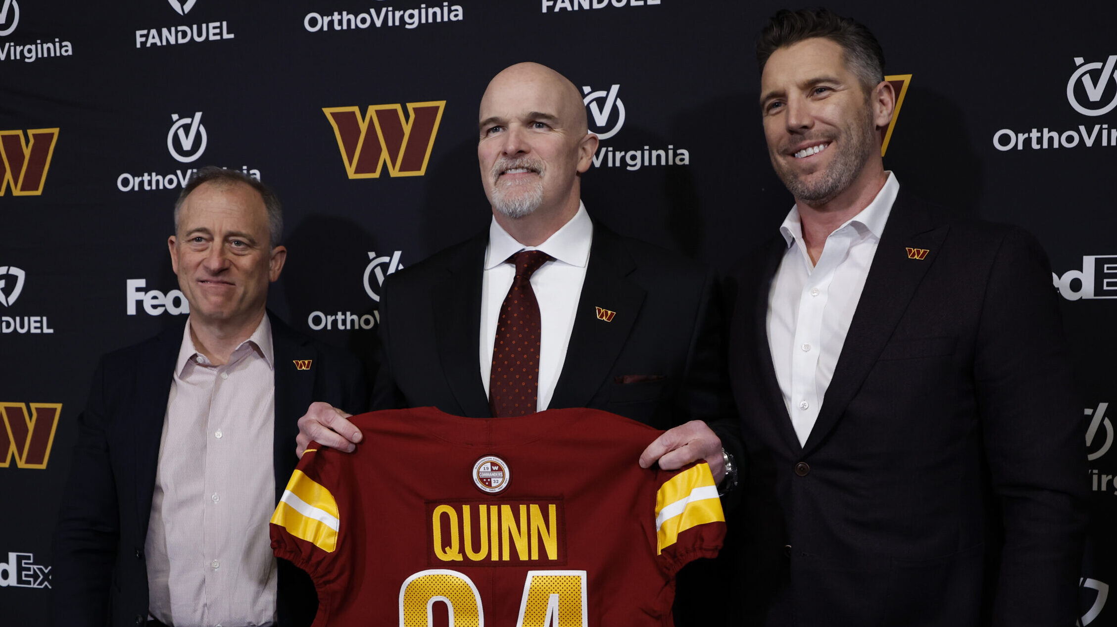 Commanders brass, owner Josh Harris, head coach Dan Quinn and GM Adam Peters stand together for Quinn's introductory press conference.