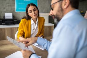 Male and female colleagues discussing paperwork at conference table