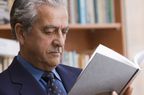 Man in suit reading book in library