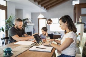 A person works on a laptop while hanging out with family.