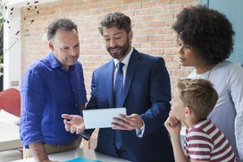 Financial advisor with digital tablet meeting with family in kitchen