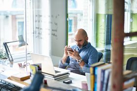 Man looking at cell phone in his office