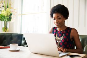 A woman reviews her investment gains on laptop at home