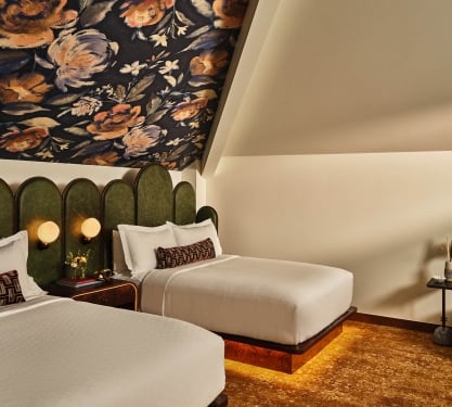 Two queen beds and seating area in the Deluxe Loft Guest Room at the Crawford Hotel in Denver, Colorado.