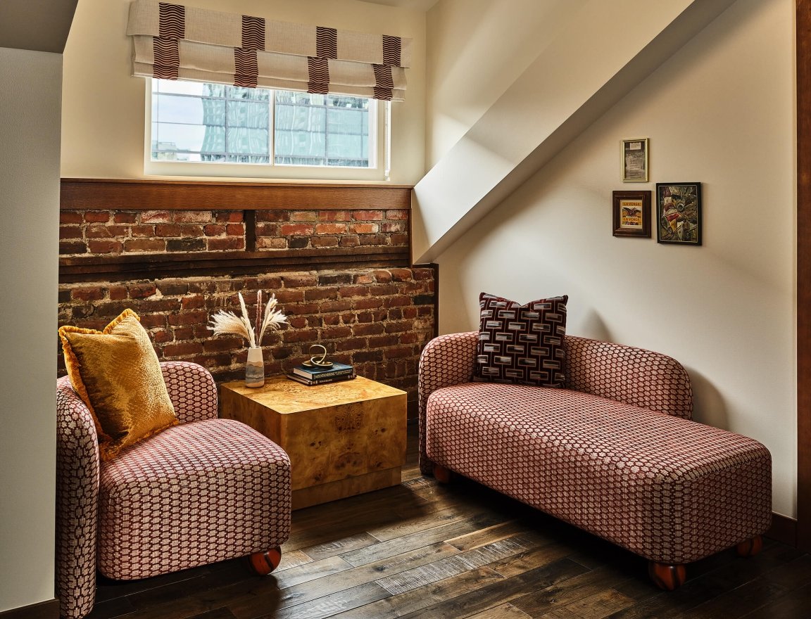 Seating area with a chair and chaise lounge in the Deluxe Loft Guest Room at the Crawford Hotel in Denver, Colorado.