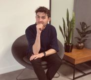 This is an image of a white man sitting in an office. He has on dark clothing