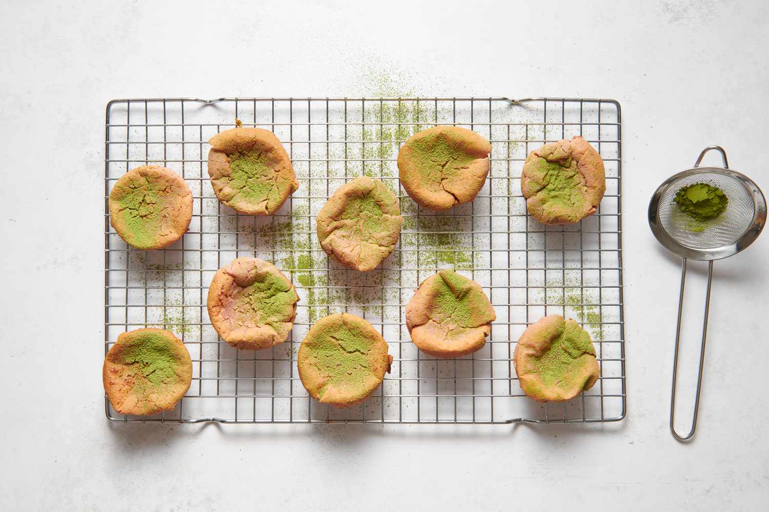 Strawberry miso mochi muffins on a cooling rack, topped with matcha powder