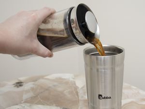 Hand pouring coffee from french press into Bubba Envy Insulated Stainless Steel Tumbler