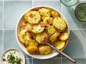 A serving bowl of German potato salad topped with chopped parsley 