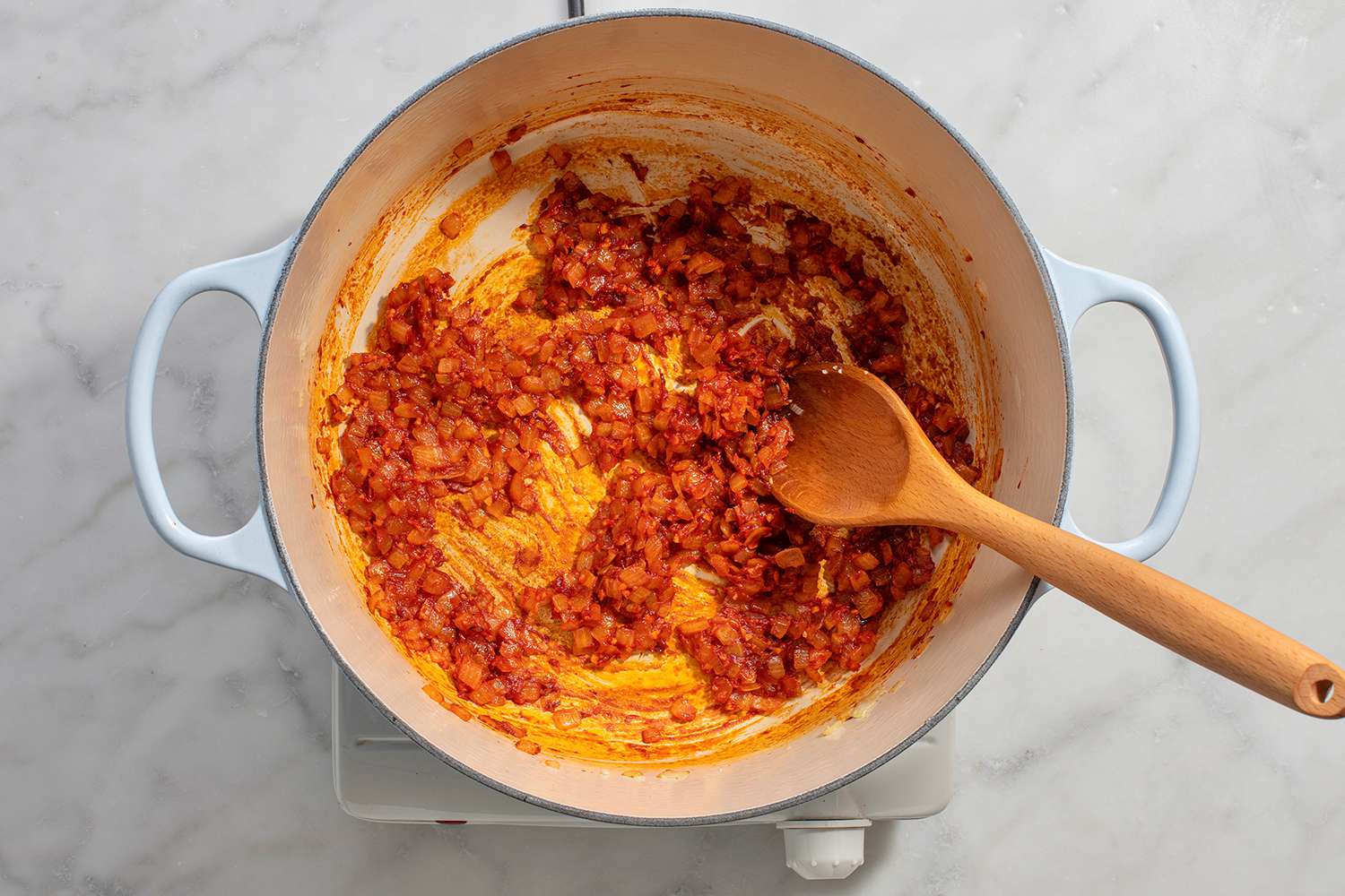 Tomato paste cooking in the dutch oven with onions and garlic