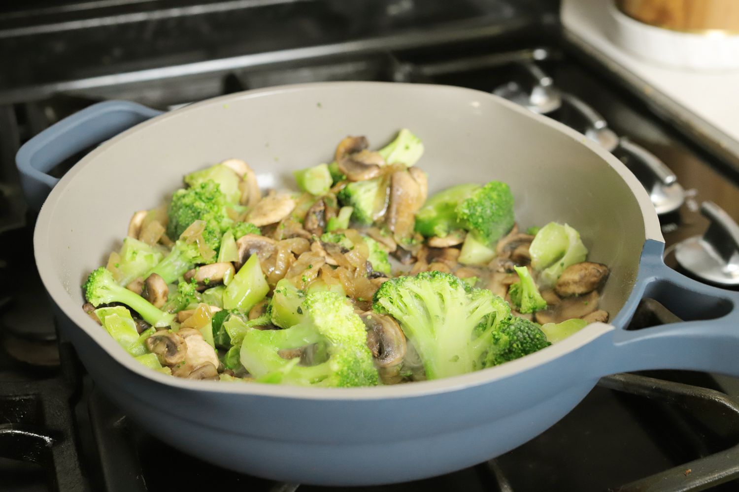 Broccoli stir fry in a blue Always Pan on a gas stove