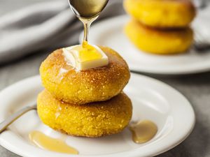 Old-fashioned hot water cornbread with butter and syrup on a plate