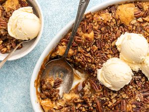 Pecan pie cobbler in a casserole dish with vanilla ice cream