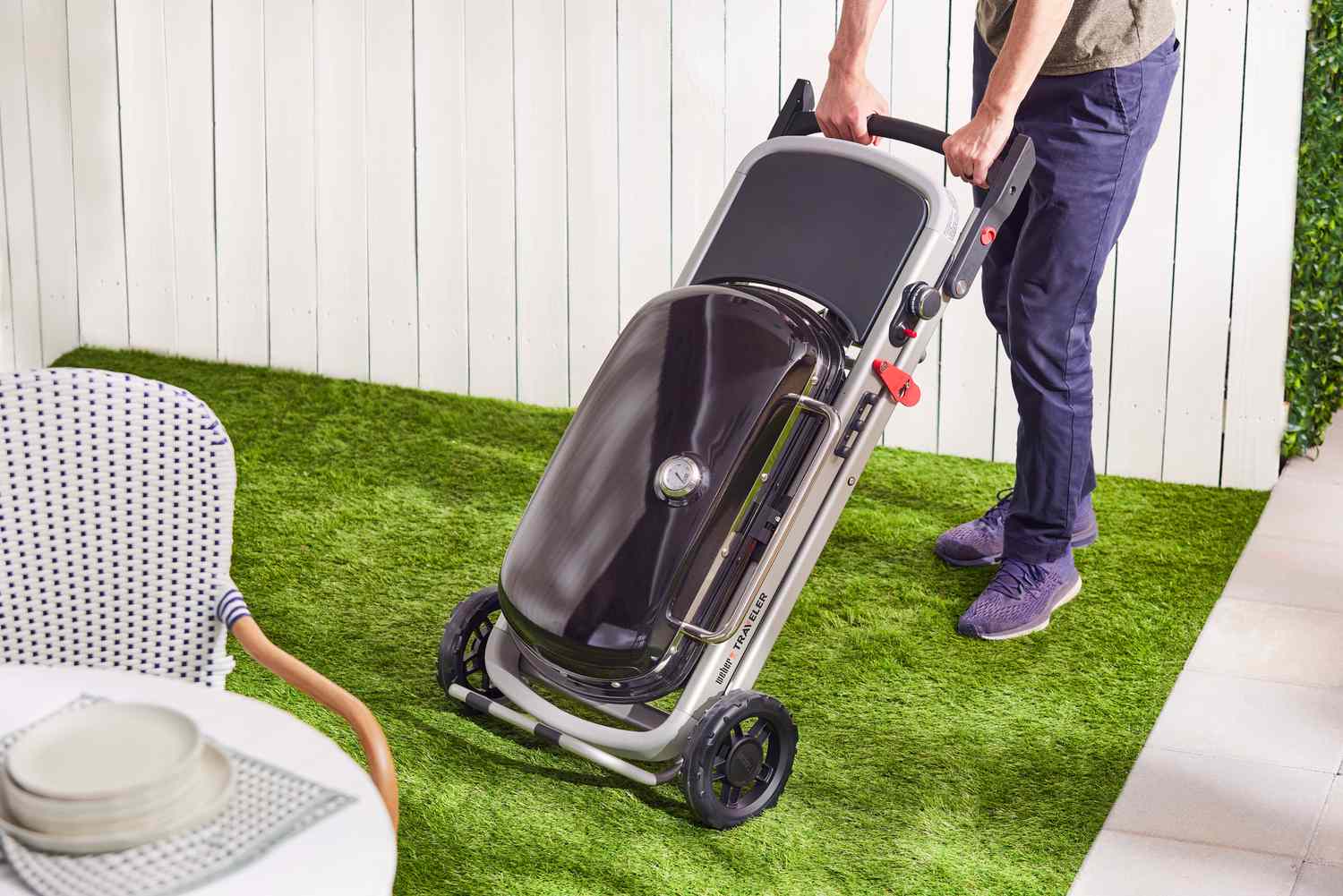 A person wheeling the compacted Weber Traveler Portable Gas Grill