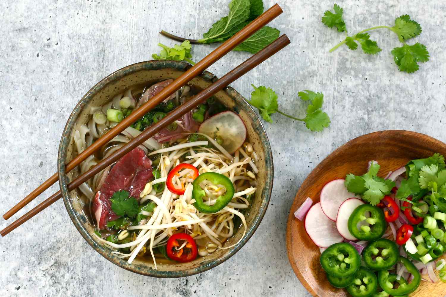 Bowl of Instant Pot beef pho with garnishes.