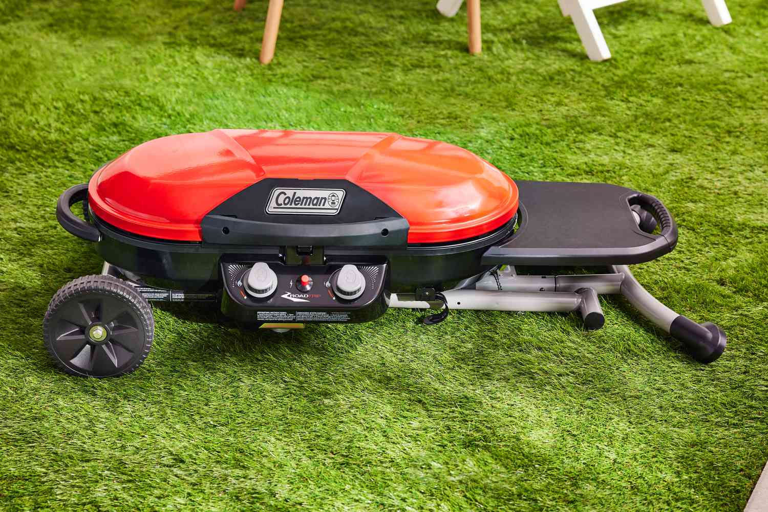 A Coleman Roadtrip portable grill sits on the grass