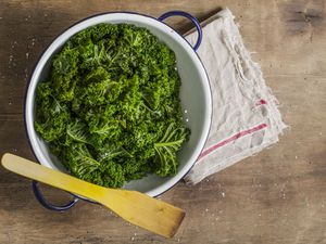 Steamed green cabbage in colander, wooden spoon
