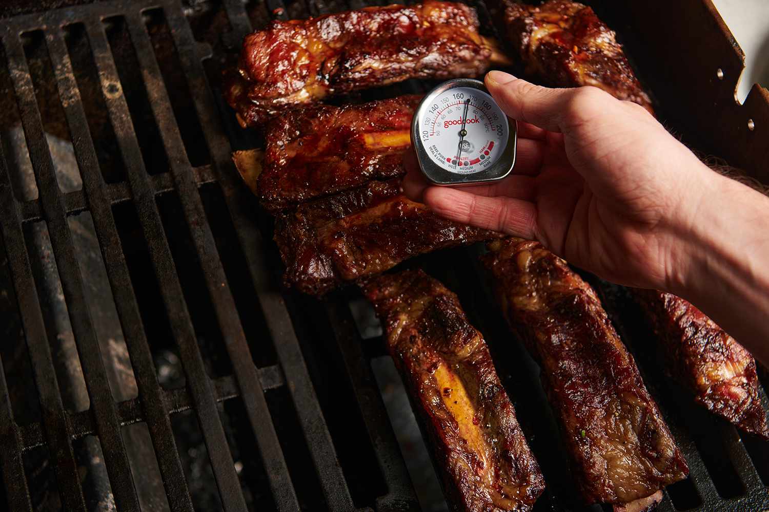 Tender slow-grilled beef ribs on the grill, with a thermometer 
