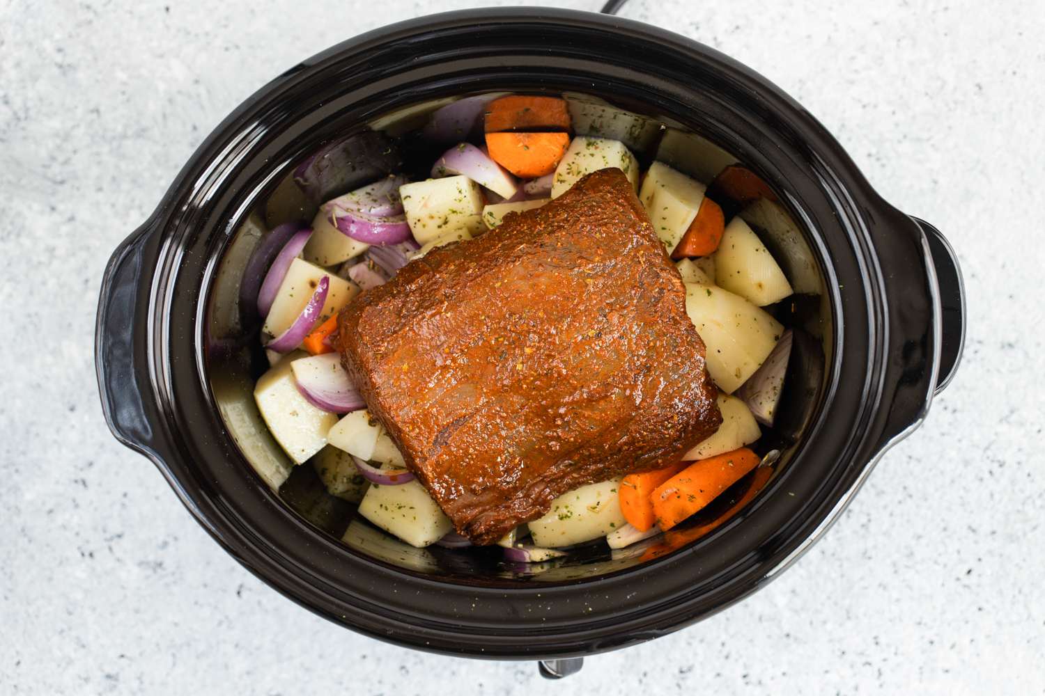 Tri-tip roast placed on top of vegetables in the slow cooker