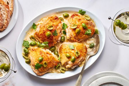 A platter of three martini chicken, topped with green olives and parsley, served with crusty bread and dirty martinis.