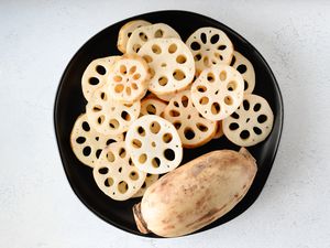 whole and sliced lotus root on a black plate