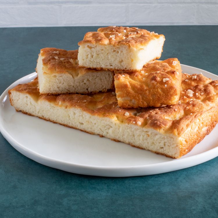 Golden squares of focaccia stacked on a white plate