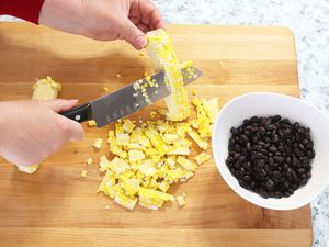 Hand shucking corn with the Zwilling J. A. Henckels Twin Signature 7-Inch Hollow Edge Santoku Knife 