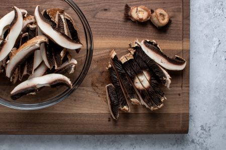 Sliced mushrooms on a cutting board and in a glass bowl 