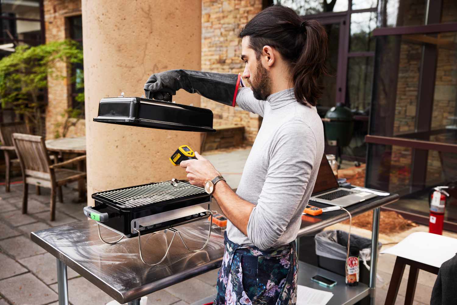 Person lifting the lid from the Weber Go-Anywhere Charcoal Grill while measuring the temperature with a thermometer 