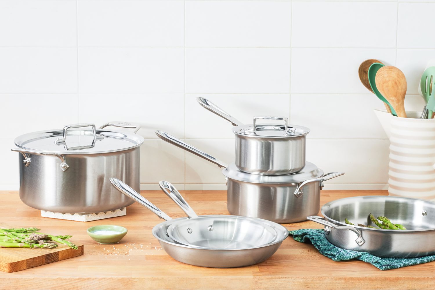 All-Clad D5 Stainless Brushed 5-Ply Bonded Cookware Set displayed on a wooden counter