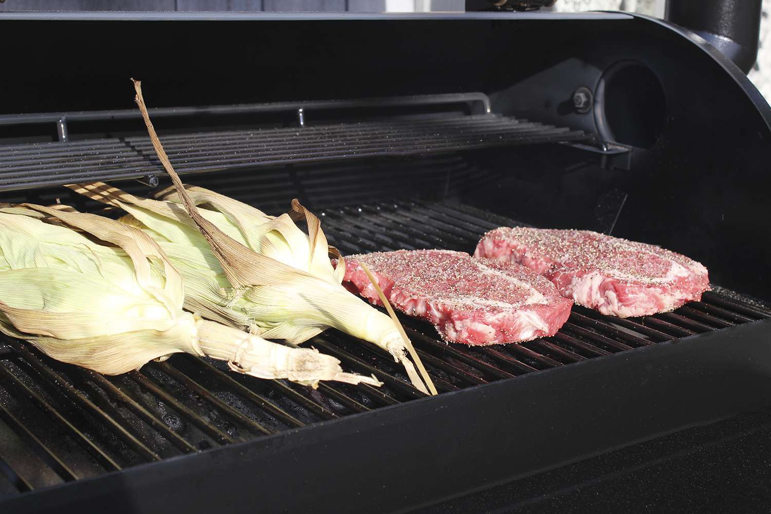 Corn and seasoned raw steaks on the Z Grills 450A Wood Pellet Grill & Smoker