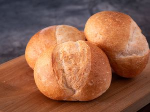 Three Brotchen dinner rolls on a wooden surface