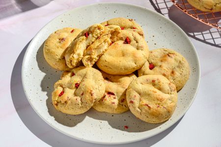 A plate of strawberry cheesecake cookies, with one ripped open showing a cream cheese center