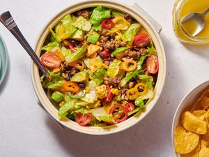 A taco salad served with tortilla chips and extra dressing