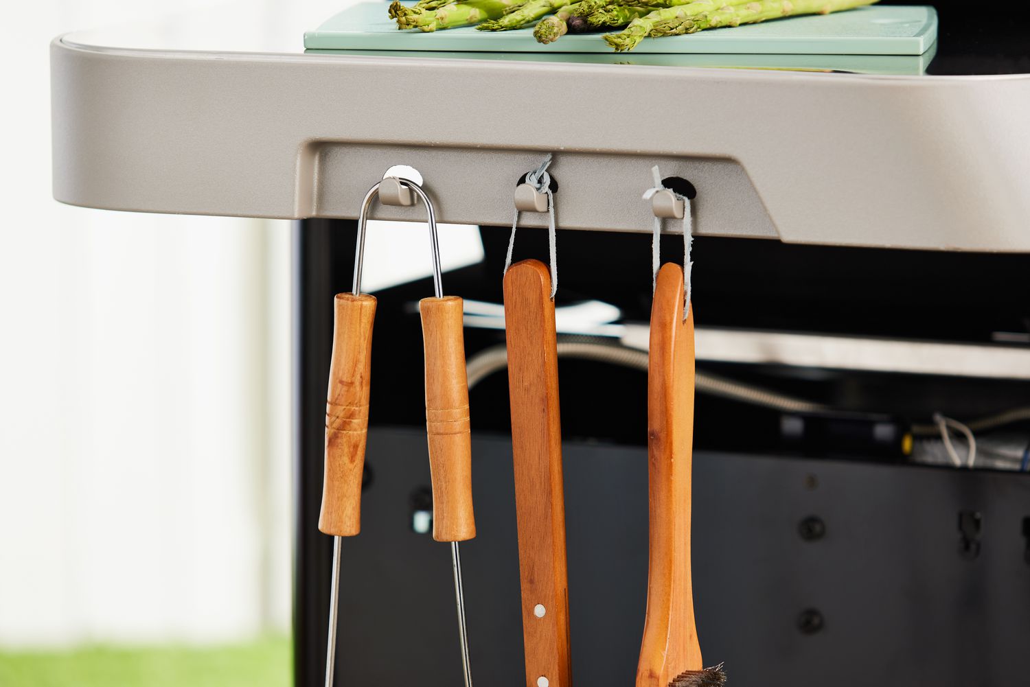 Grill utensils hanging on hooks on the side of the Weber Genesis EX-325S Propane Gas Smart Grill