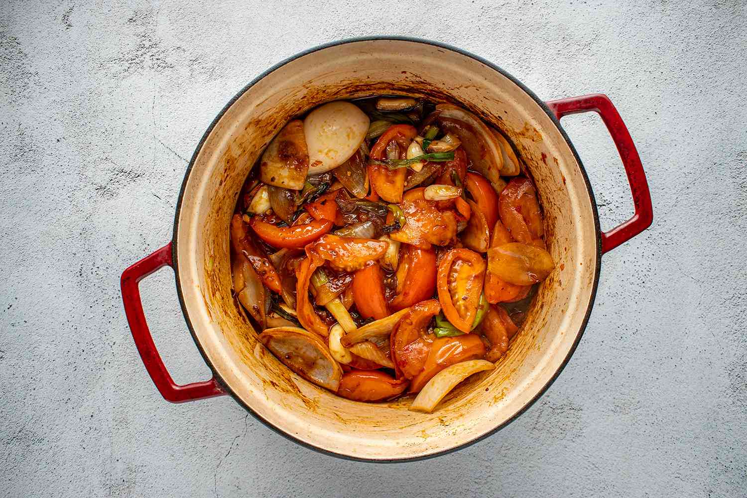 Garlic, ginger, green onions, onion, chili, spicy bean paste, and tomatoes in a pot