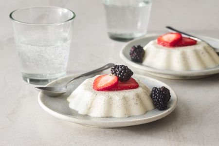 Two servings of vanilla panna cotta, stopped with sliced strawberries and blackberries