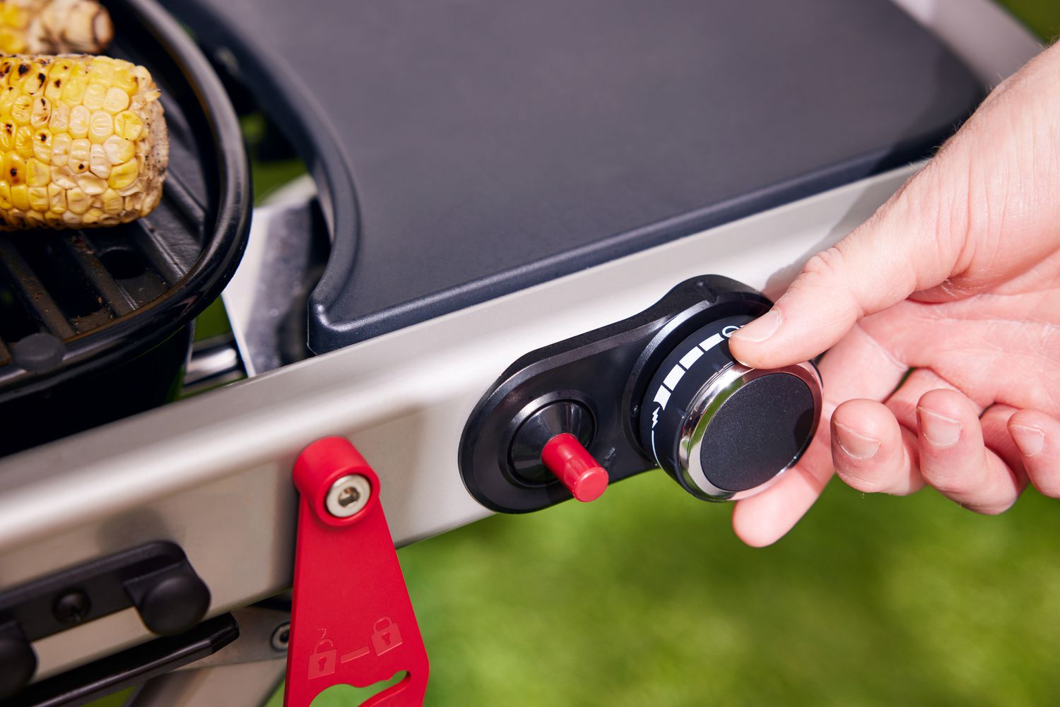 A person's hand turning the dial on the Weber Traveler Portable Gas Grill