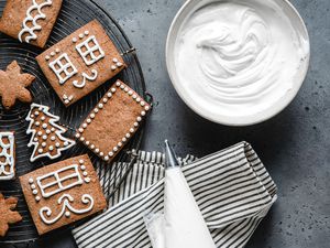 Royal Icing in a bowl alongside decorated gingerbread house cookies